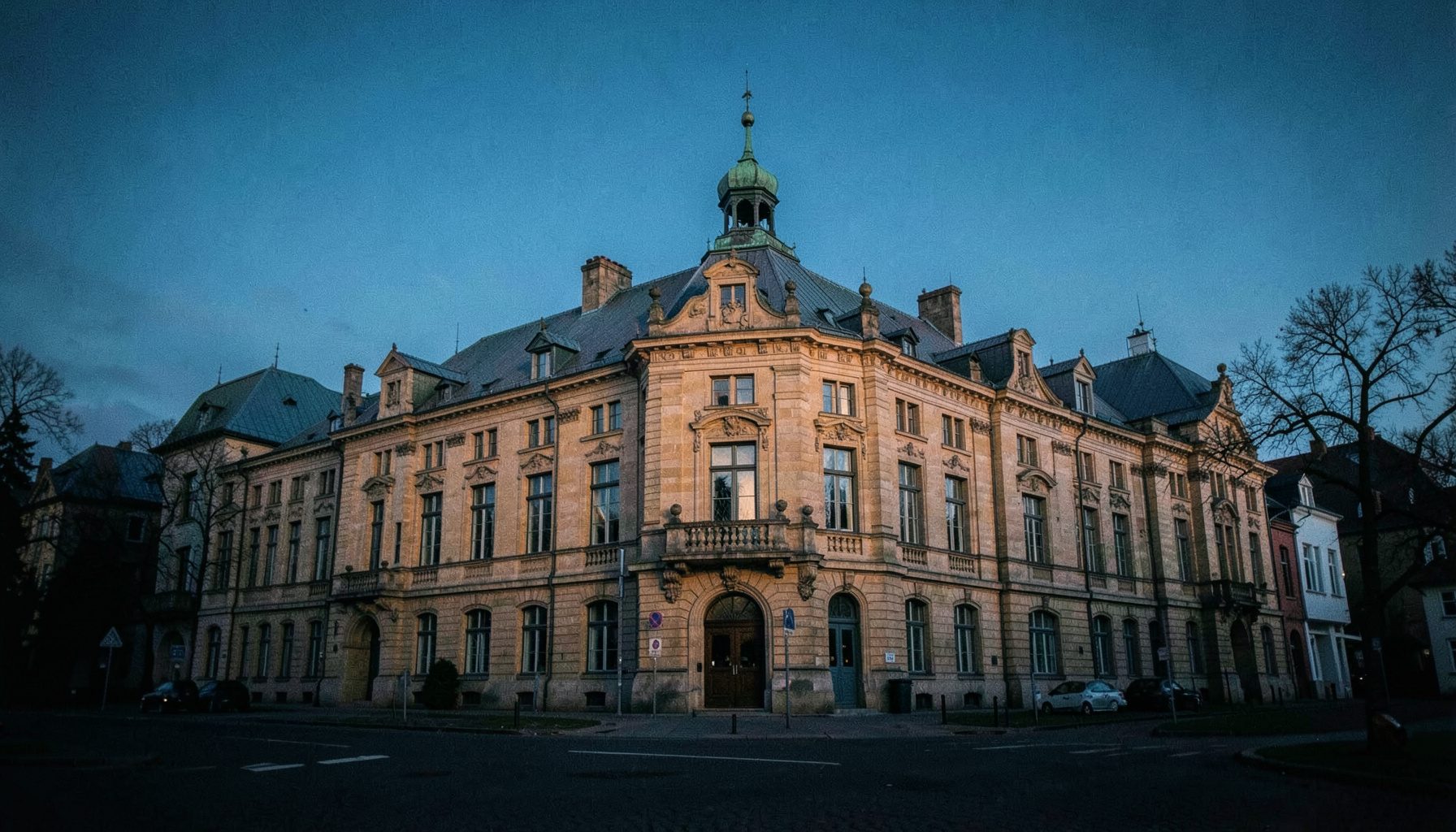 En stilla vy över Stora Kronohuset i Kristianstad i mjukt eftermiddagsljus, med varma sandstensfärger och djupblå himmel